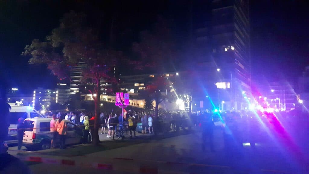 Blyški nuotrauka iš riaušių prie Seimo: žmonių figūros, policijos švyturėliai, tamsūs pastatai