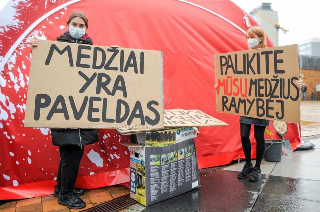 Dvi protestuotojos laiko plakatus: "Medžiai yra paveldas" ir "Palikite mūsų medžius ramybėje"