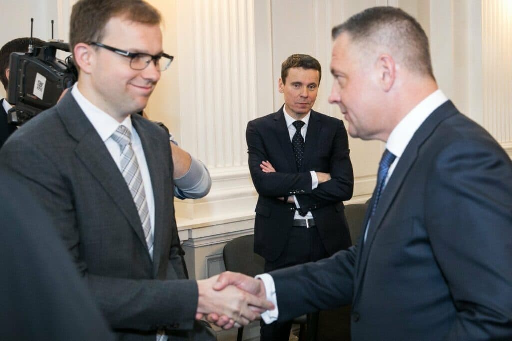 Ranką spaudžia Vytautas Gapšys ir Eligijus Masiulis, į juos šypsodamasis žiūri Raimondas Kurlianskis