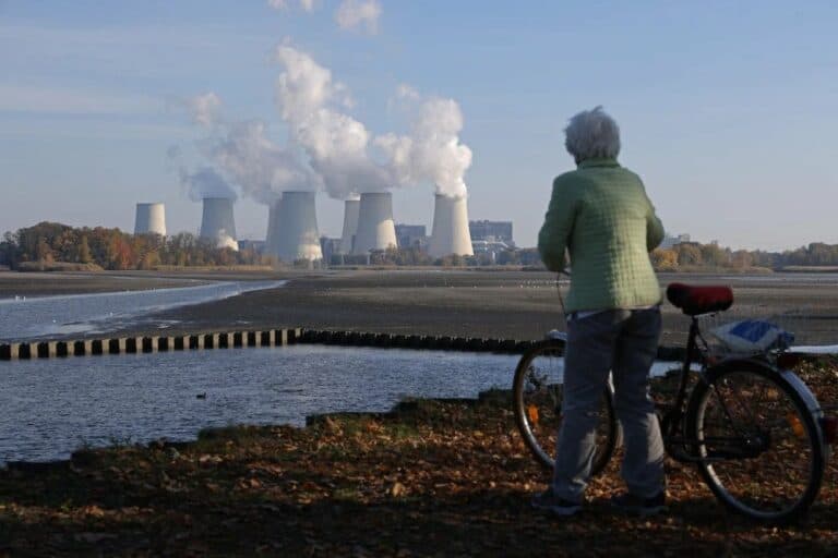 dviratininkė žiūri į elektrinės bokštus tolyje